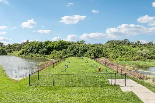 A soccer field is surrounded by a fence and a river.