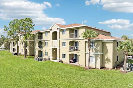 A row of apartment buildings with green lawns in front.