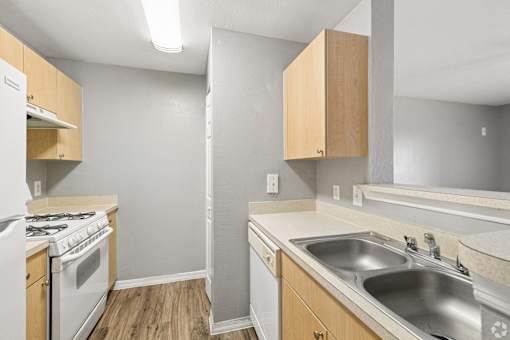 A kitchen with a stove, sink, and cabinets.