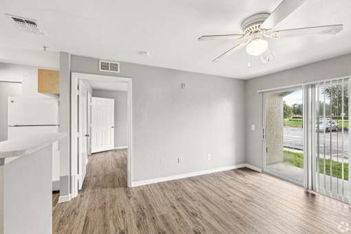 A room with a ceiling fan and sliding glass doors.