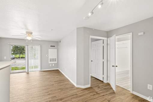 A room with a ceiling fan and sliding glass doors.