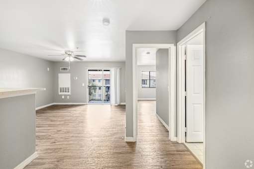 A spacious room with a ceiling fan and wooden flooring.