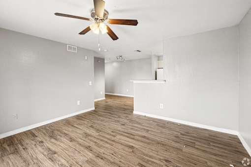 A room with a ceiling fan and wooden flooring.