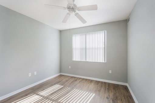 an empty bedroom with a ceiling fan and a window