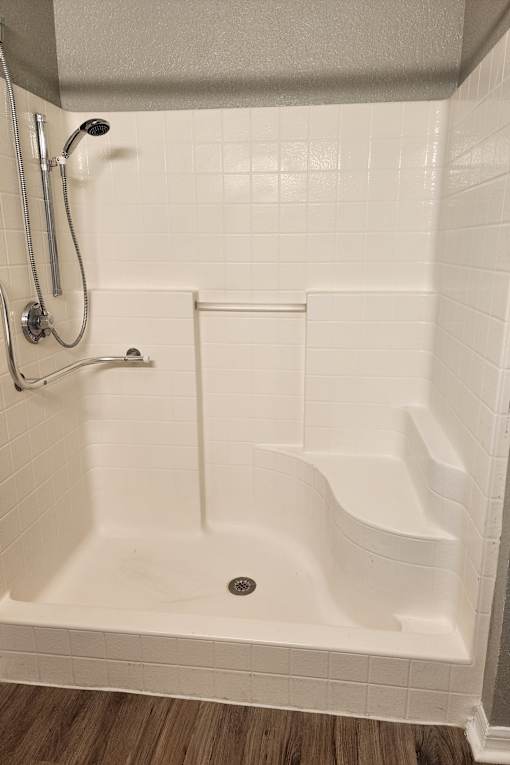 A white bathtub with a shower head and hand held shower.