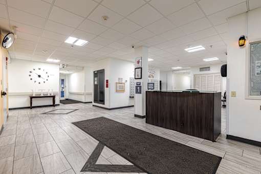 A reception area with a white wall and a black and white clock.