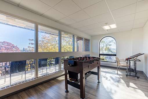 A foosball table in a room with a view of trees outside.