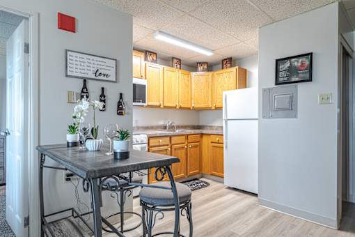 A kitchen with a table and chairs in front of a refrigerator.