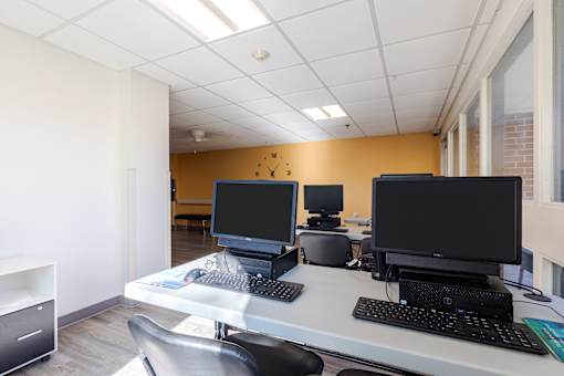 A white desk with two monitors and a keyboard.