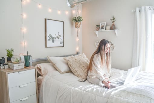 a woman sitting on a bed with a laptop computer at Bluestone Lofts, Minnesota, 55803