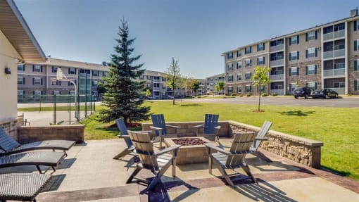 a patio with chairs and a fire pit in front of an apartment building  at Boulder Ridge, Duluth, MN 55811