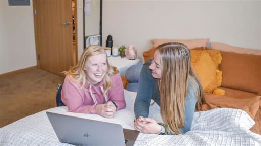 two women laying on a bed with a laptop at Boulder Ridge, Duluth, MN