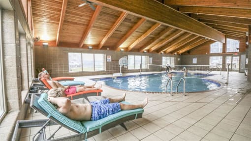 a man laying on a lounge chair next to a swimming pool at Boulder Ridge, Duluth