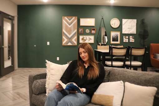a woman sitting on a couch reading a book in a living room  at Timber Ridge, Forest Lake, MN