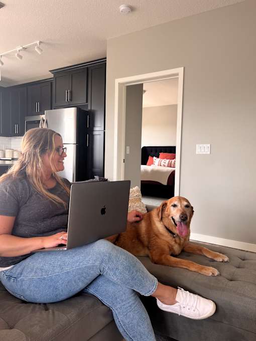 a woman sitting on a couch with a laptop computer on her lap and a dog  at Timber Ridge, Minnesota, 55025