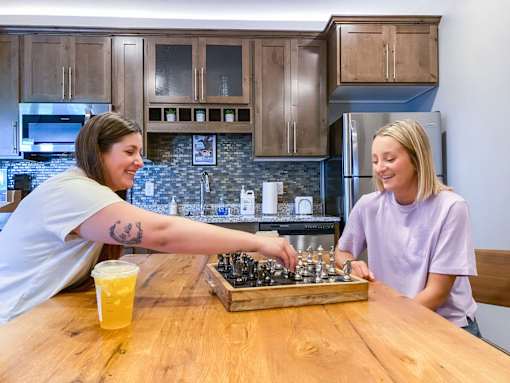 two women playing chess at a table in a kitchen  at Timber Ridge, Forest Lake