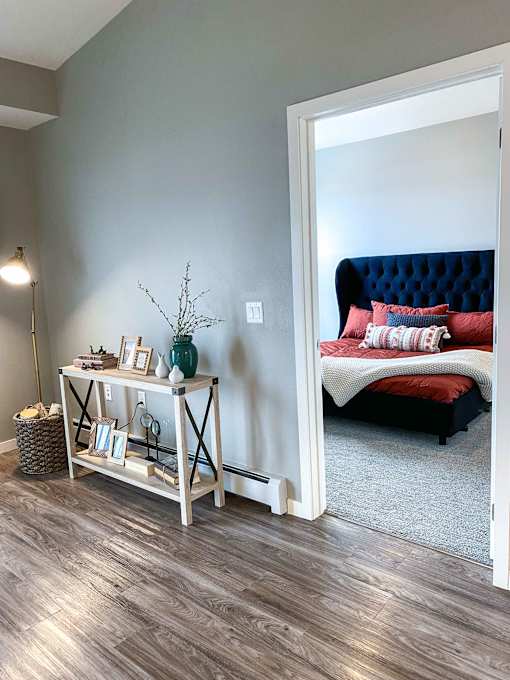 a bedroom with a bed and a white wall and wood floors  at Timber Ridge, Forest Lake, MN