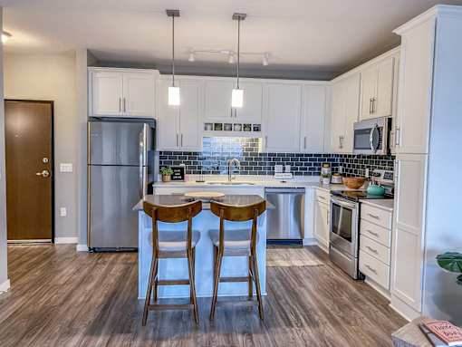 a kitchen with stainless steel appliances and two bar stools  at Timber Ridge, Forest Lake, 55025