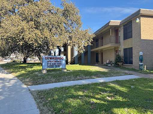 A sign in front of a building that says Demasiado Apartments.