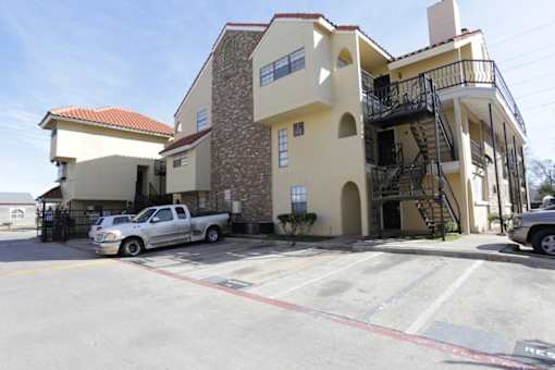 A silver truck is parked in front of a two-story building.