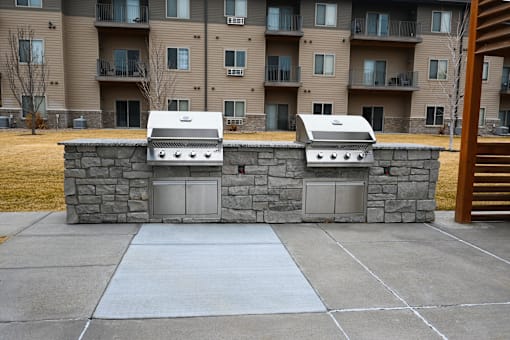 Two BBQ grills are in front of apartment buildings.