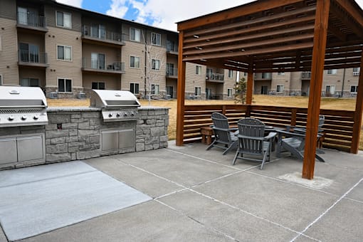 A patio with a table and chairs and a grill.