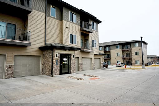 Apartment complex with a parking lot in front.