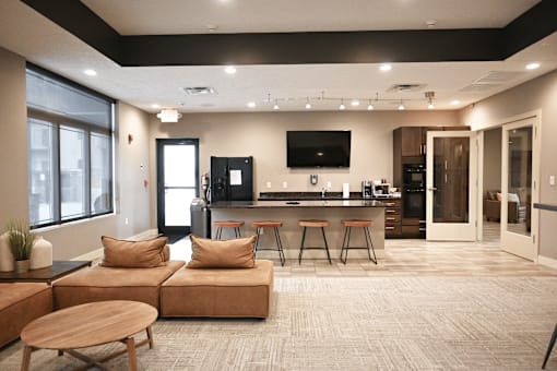 A modern living room with a kitchen area in the background.
