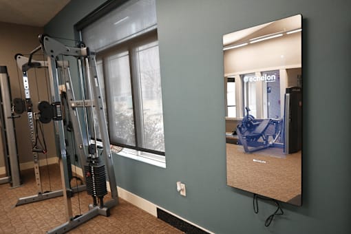 A mirror in a room with a gym equipment.