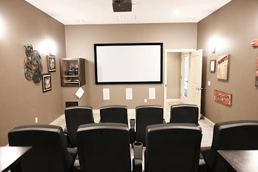 A home theater with a large screen and black chairs.