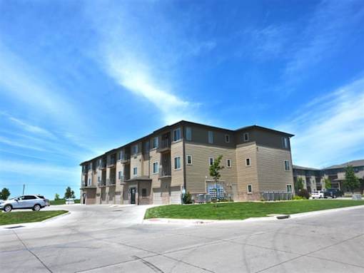 A large apartment complex with a parking lot in front at The Sterling Kearney.