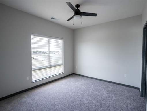 A room with a ceiling fan and a window with blinds.