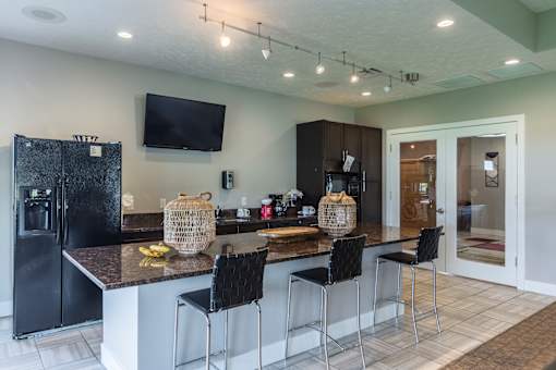 A kitchen with a black fridge and a black bar stool.