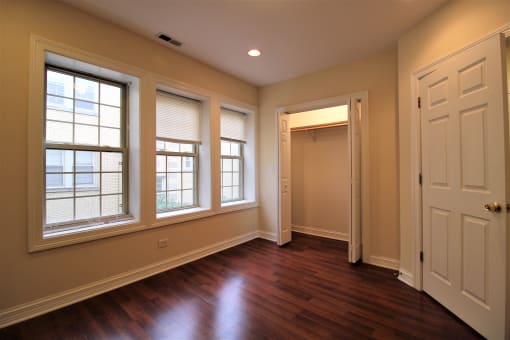 an empty living room with wood floors and large windows