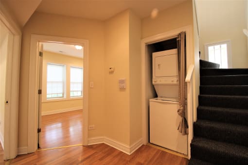 a room with stairs and a refrigerator and a washer and dryer in it