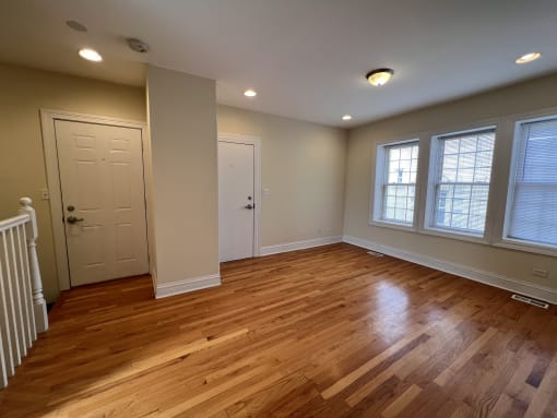 an empty living room with wooden floors and a white door