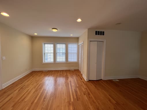 an empty living room with wooden floors and a door to a closet