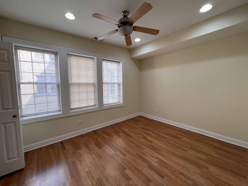 an empty living room with a ceiling fan and windows