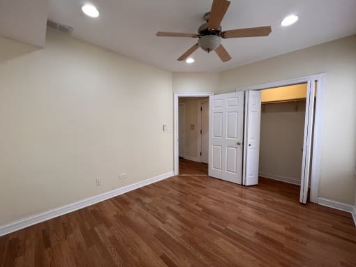 an empty living room with wooden floors and a ceiling fan