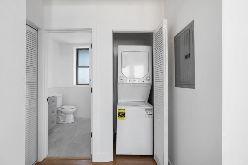 a white bathroom with a washer and dryer and a door to a white