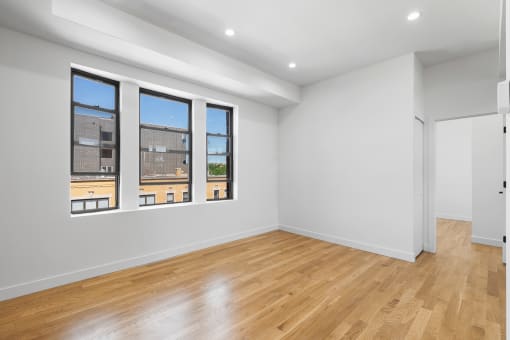 a living room with a hardwood floor and three windows