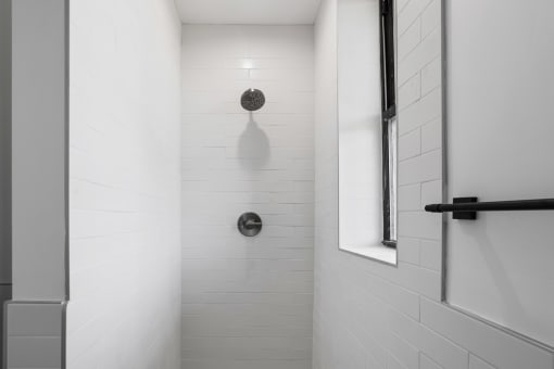 a white tiled shower in a bathroom with a window