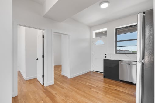 an empty kitchen with white walls and wood floors