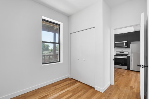 an empty room with white walls and wood floors and a window