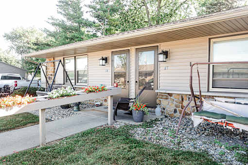 A small house with a porch and a bench.