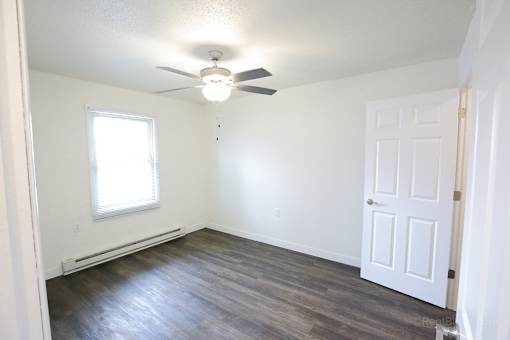 A room with a ceiling fan and a door.
