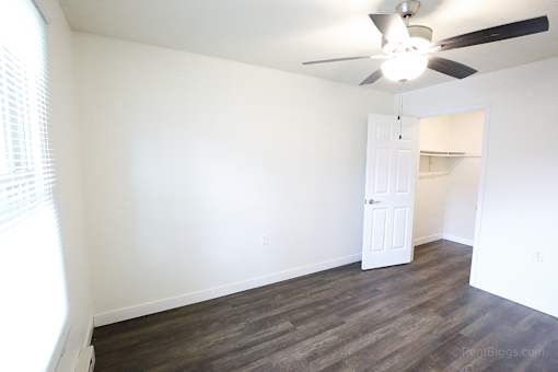 A room with a ceiling fan and a door.