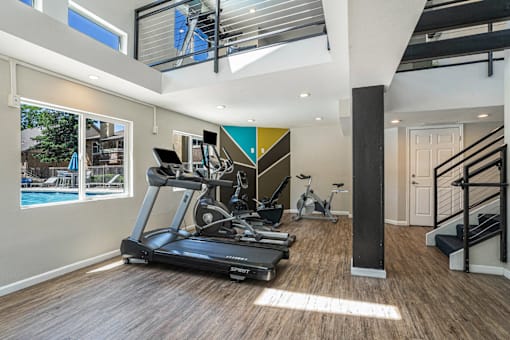 A spacious home gym with a treadmill, exercise bike, and a staircase.