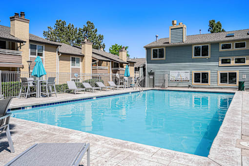 A swimming pool surrounded by lounge chairs and umbrellas.