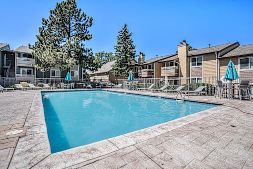 A swimming pool surrounded by a patio and chairs.